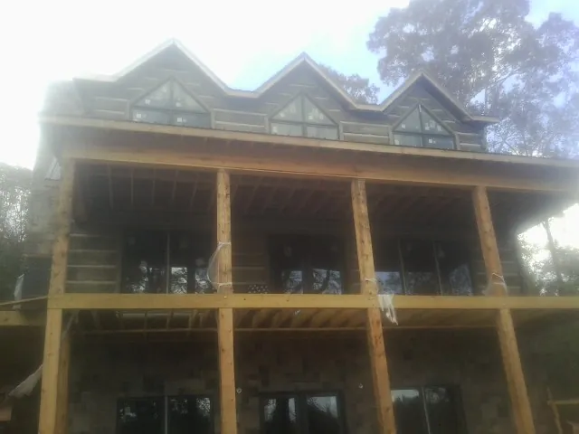 Dormers and porch framing on a large log home under construction — Roof Coating work by our crew in Wesley Chapel