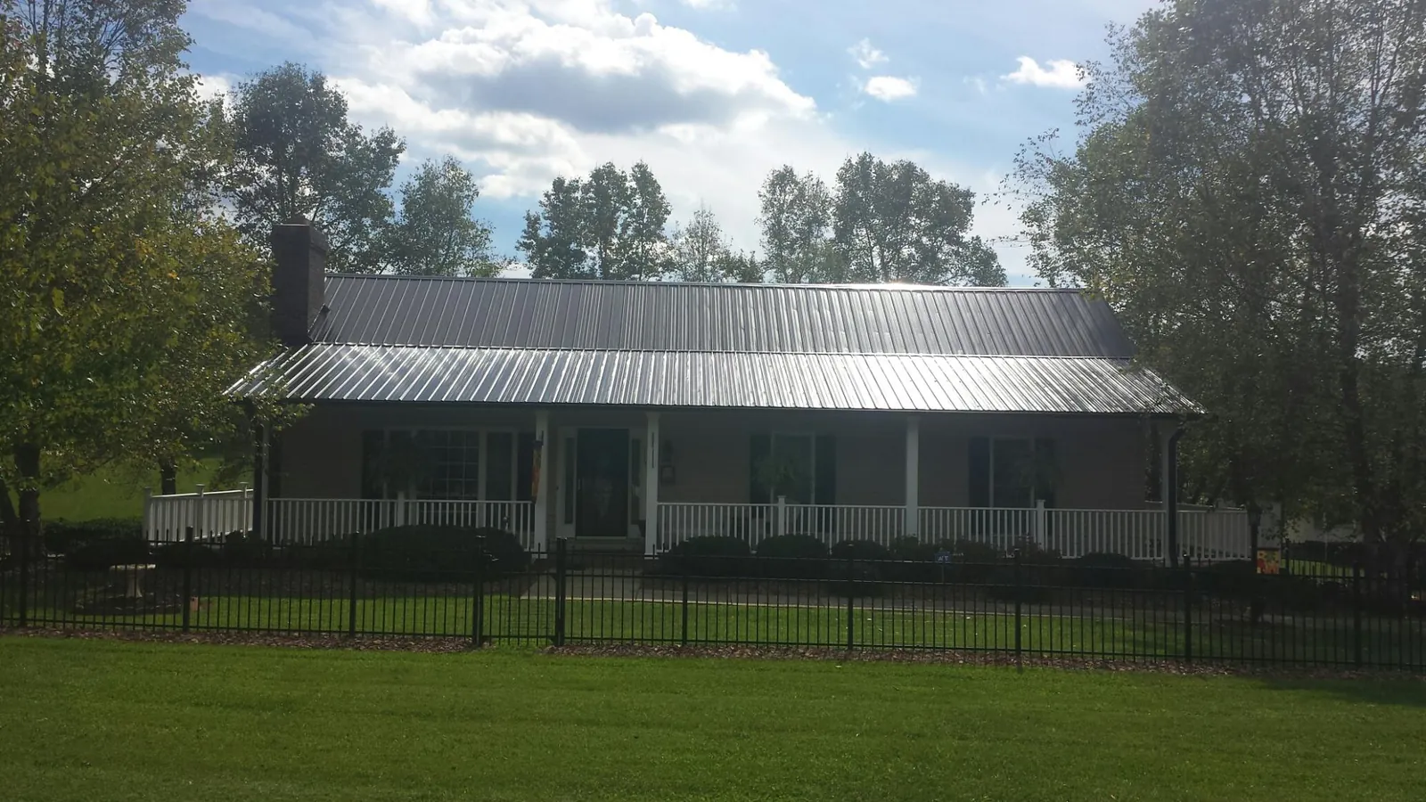 Gray metal roof on a brick ranch with a full width front porch — Gutter Guard Installation work by our crew in Wesley Chapel