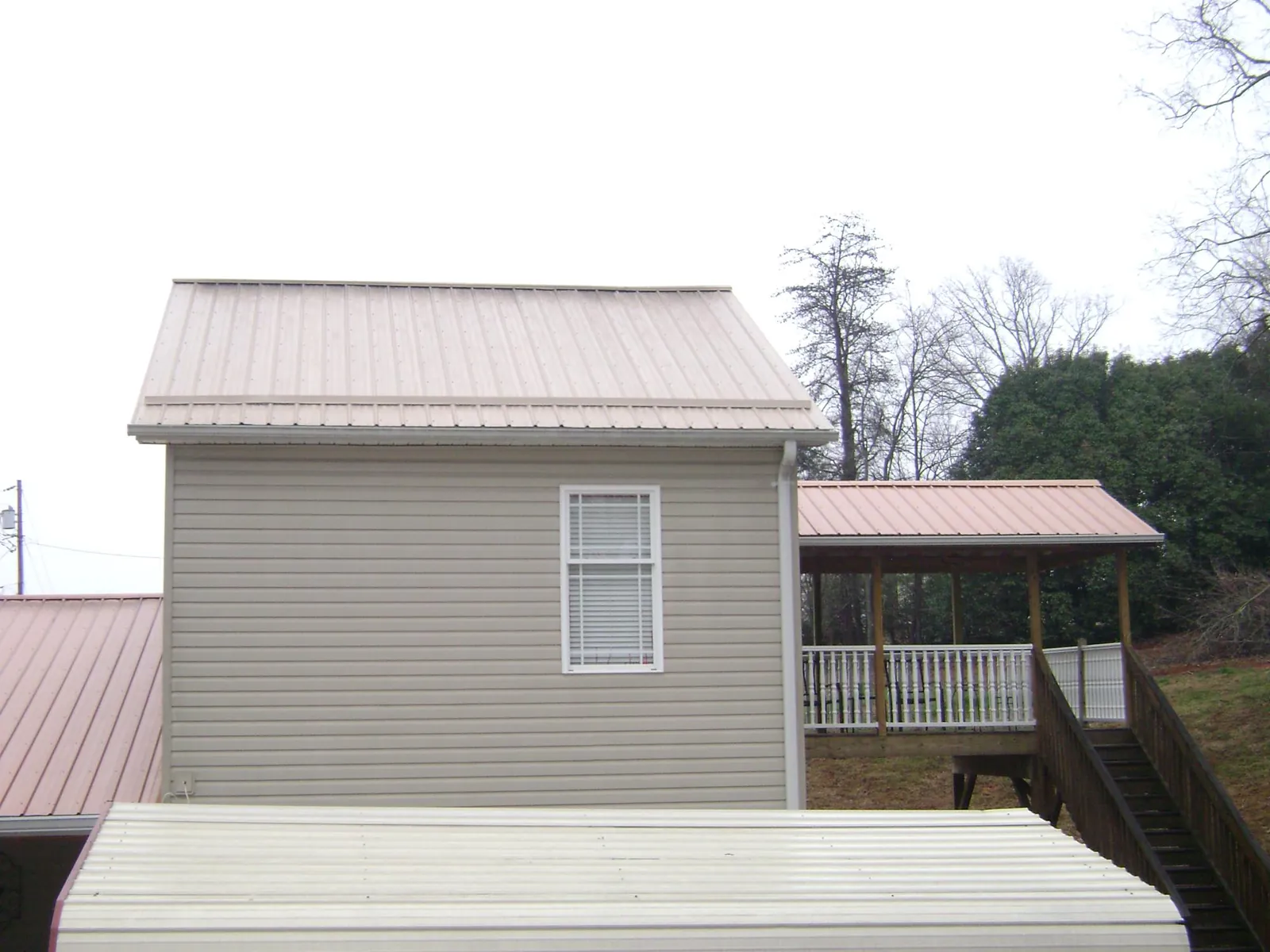 Tan metal roofs on a two story addition and attached porch, from a Roof Replacement job in Wesley Chapel