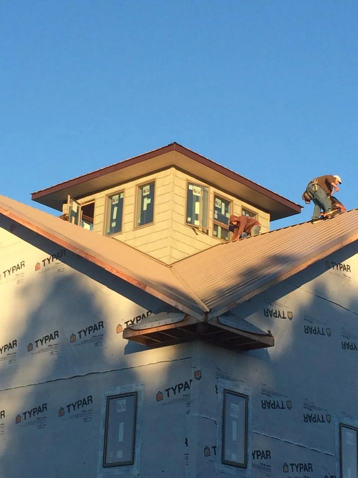 Roofers working around a rooftop cupola on a new metal roof at sunset — Roof Waterproofing in Wesley Chapel by Roofing Brothers